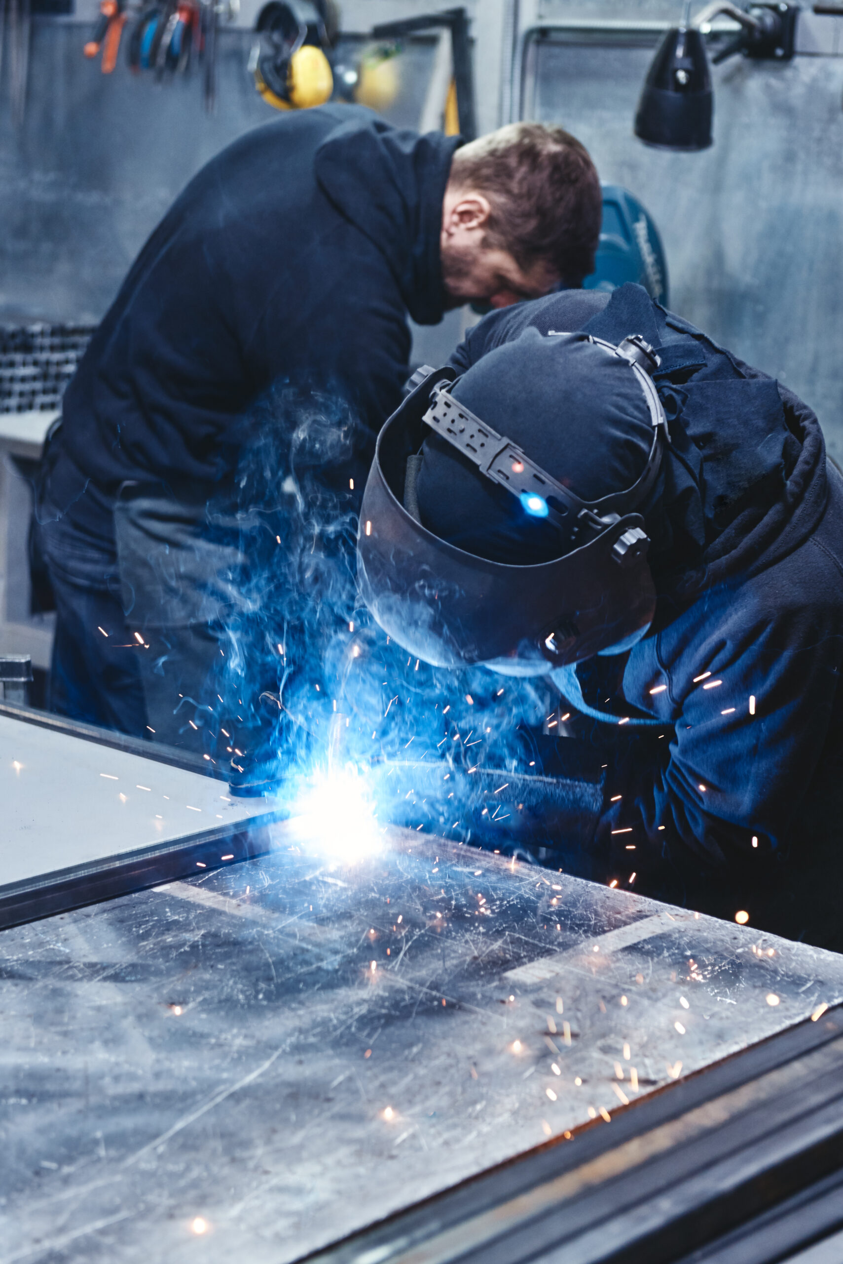 Experts in the Industry. Male worker wearing protective clothing repair steel construction Excavator bucket dropping dirt into an open trench.