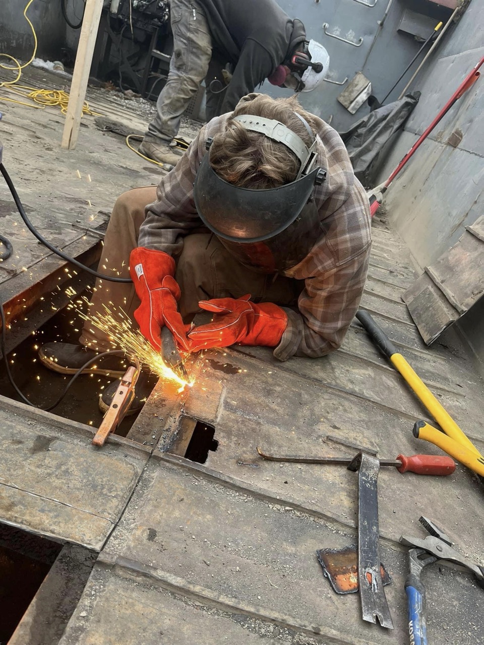 Excavator bucket dropping dirt into an open trench.
